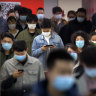 Commuters wear face masks to protect against the spread of new coronavirus as they walk through a subway station in Beijing.
