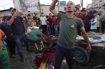 A youth reacts while other residents inspect a wounded horse near a damaged car that was hit in an Israeli airstrike that killed people in the car and the horse cart, at the main road in Gaza City, on Sunday, August 7.