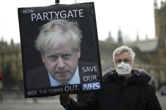 Muhafazakar Parti karşıtı bir protestocu, İngiltere Başbakanı Boris Johnson'ın resmini içeren bir pankart taşıyor.