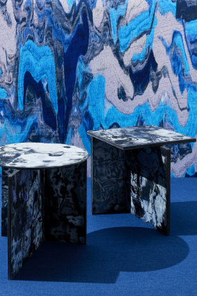 Tables by Sophie Rowley in Bahia Denim, a material made from leftover scraps of jeans, in front of a poster by Penadés, made from a scan of his Structural Skin.
