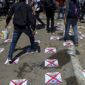 Protesters walk on a road with defaced images of General Min Aung Hlaing, in Yangon, Myanmar.
