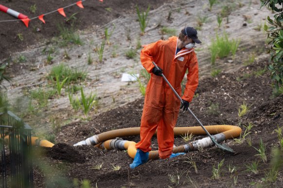 A worker removes mulch at Rozelle Parklands, which is closed after the discovery of asbestos at multiple locations. 