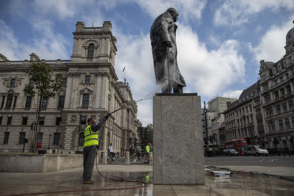 A worker cleans graffiti from the statute of former prime minister Winston Churchill.