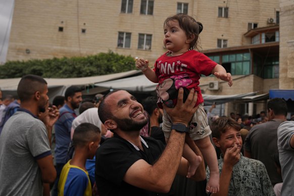 Warga Palestina merayakan pengumuman rencana perdamaian di luar Rumah Sakit Al-Aqsa di Deir al-Balah, Jalur Gaza tengah, pada hari Kamis.