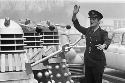 Filming at Shepperton Studios of ‘Daleks Invade Earth’. Bernard Cribbins, who appears as a Policeman, attempts to control the Daleks in the road outside the studio, 1966.