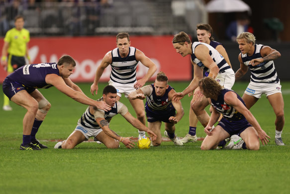 Players fight for the ball at a wet Optus Stadium.