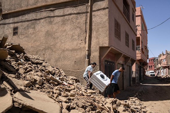 People recover a washing machine from their home in the town of Amizmiz, near Marrakech.