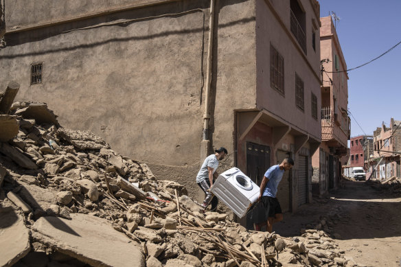 People recover a washing machine from their home in the town of Amizmiz, near Marrakech.