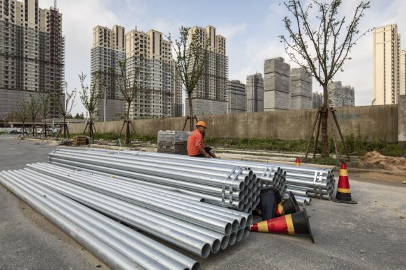 A worker sits on a pile of steel pipes near an under construction residential housing developments in Shanghai, China.