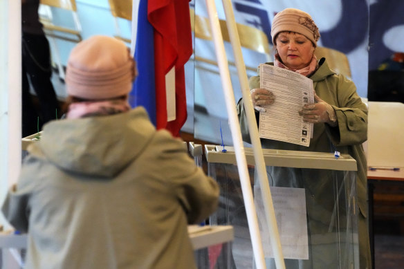 A woman reflected in a mirror casts her ballot during the State Duma, the Lower House of the Russian Parliament and local parliament elections at a polling station in Saint Petersburg, Russia.