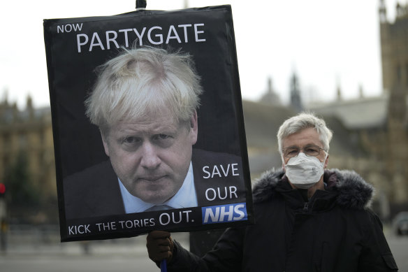 An anti-Conservative Party protester holds a placard with an image of British Prime Minister Boris Johnson.