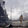 A firefighter looks up the rubble and wreckage of a burnt-out marketplace following an earthquake in Wajima.