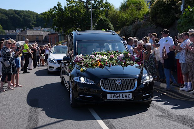 Fans of singer Bonnie Tyler line the streets as her coffin is transported in a hearse back to her former home ahead of her funeral, in Mumbles, Wales