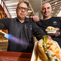 George Milonas (left) blowtorches a lobster roll. He’s joined by his business partner Luke Louca.