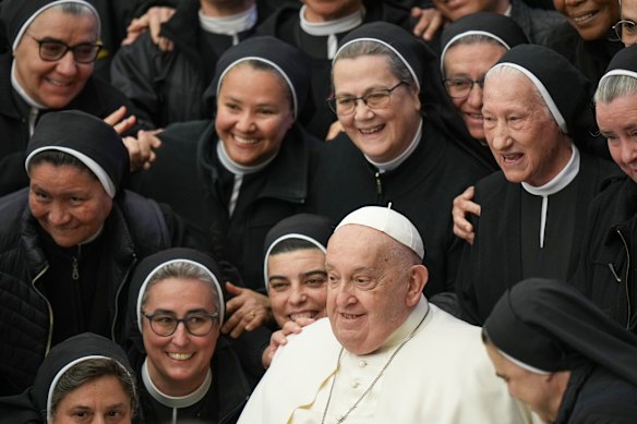 Pope Francis poses for photos with a group of nuns during his weekly general audience in the Pope Paul VI Hall at the Vatican on February 5, 2025.