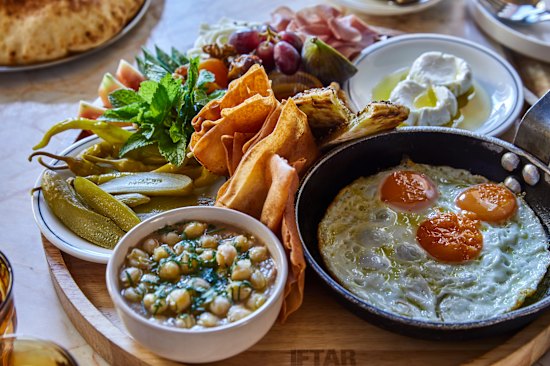 Breakfast board loaded with fried eggs, ful medames, zaatar manoush, labneh, cold-cuts, assorted pickles, fresh vegies and village cheeses.