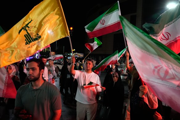 A man holds up a flag of Lebanon’s militant Hezbollah group as the others hold Iranian flags during a pro-government gathering in Tehran on Sunday, 