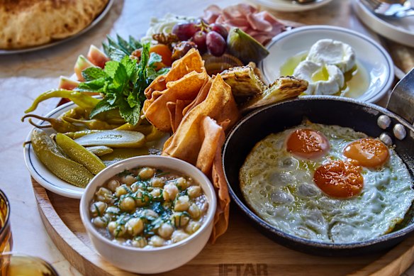 Breakfast board loaded with fried eggs, ful medames, zaatar manoush, labneh, cold-cuts, assorted pickles, fresh vegies and village cheeses.