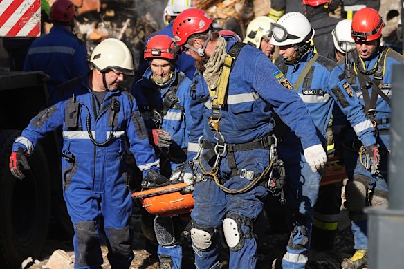 Firefighters carry a victim’s body from a building hit by Russian strikes.