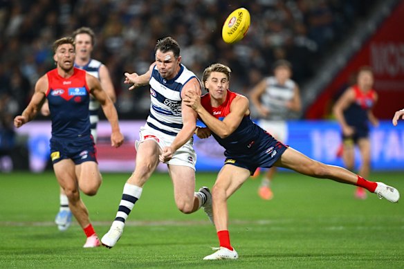 Patrick Dangerfield gets a kick away under pressure by Caleb Windsor.