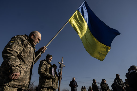 A soldier holds a flag during a military funeral for two Ukrainian  soldiers killed in Kursk.