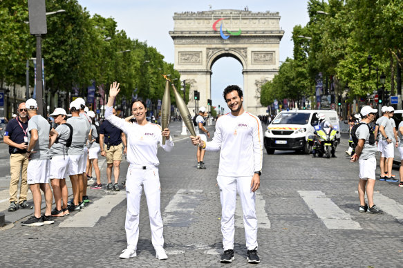 Nina Metayer, French pastry chef and Amir, French-Israeli singer-songwriter carry the Olympic Torch at the Arc de Triomphe.