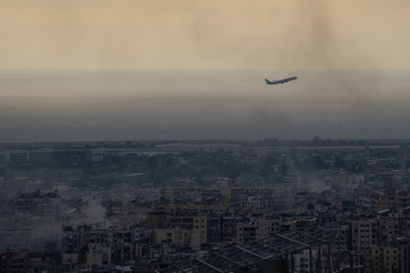 A plane departing Beirut flies near smoke from Israeli air strikes on October 6, 2024.