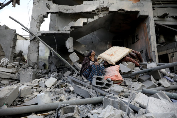 A Palestinian woman sits amid the rubble of her home.