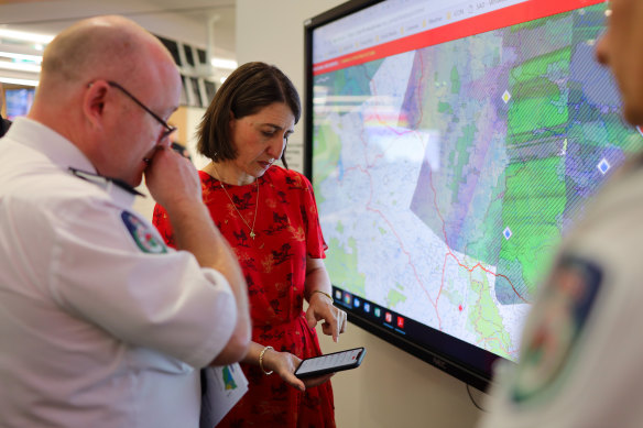 RFS Commissioner Shane Fitzsimmons shows NSW Premier Gladys Berejiklian a map of fire affected areas before a press conference in January.