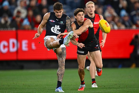 Lachlan Cowan of the Blues kicks whilst being tackled by Sam Durham of the Bombers.