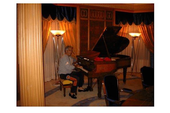 Jeffrey Epstein takes a seat at a piano.
