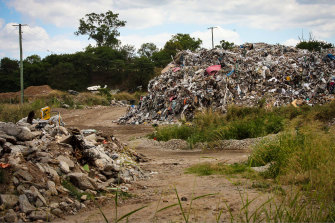 In the background: The white tip of the recycling machine is just visible between the mounds of waste at Cleanaway's Willawong recycling facility. Drivers frequenting the facility said it was rarely seen working.