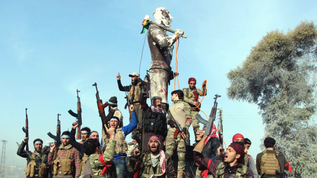 Turkish forces and their allies celebrate around a statue of Kawa, a mythological figure in Kurdish culture, prior to destroying it in the centre of Afrin in Syria.