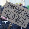 A poster with the inscription 'Justice for George' and 'Antifa on the offensive' is held by a protester demonstrating against police brutality.