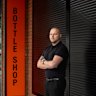 Chris Thompson outside his bottle shop in Oakleigh that will have to take down its roller shutter soon.