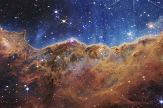 This landscape of “mountains” and “valleys” speckled with glittering stars is actually the edge of a nearby, young, star-forming region in the Carina Nebula, as captured by the James Webb telescope.