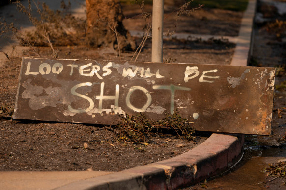 A homemade sign sits on the ground near homes destroyed by the Palisades fire in Los Angeles.