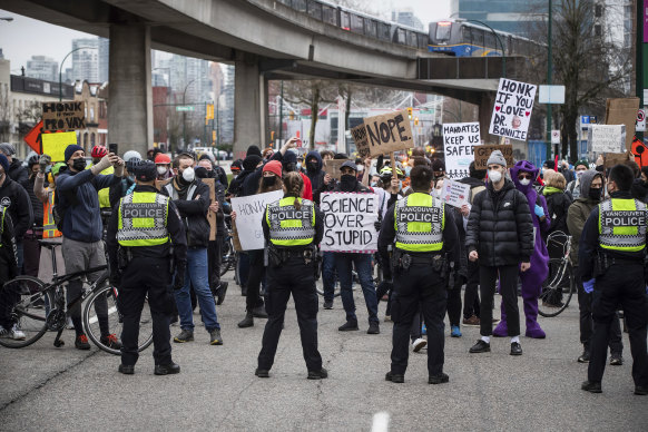 Police officers form a line in front of counter protesters blocking a convoy of truckers opposed to COVID-19 health measures and vaccinations, in Vancouver, British Columbia.