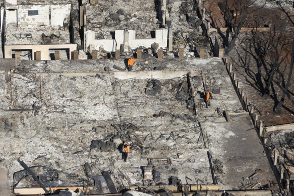 Emergency personnel conduct searches in properties destroyed by wildfires in Lahaina, on Friday.