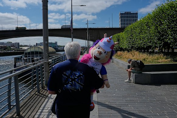 A woman carries Finnie, the Games, mascot as she walks by the River Clyde.