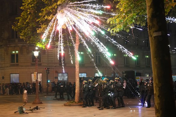 Fireworks explode over riot police  on the Champs-Elysees after the Champions League final soccer match between Paris Saint-Germain and Inter Milan.