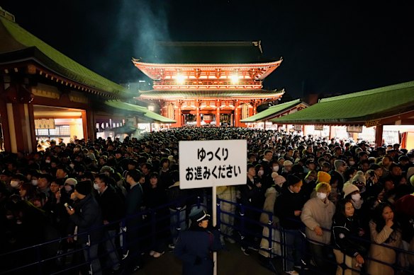 People wait in line before praying, on their traditional New Year’s pilgrimage at the main hall of Sensoji Buddhist temple in Tokyo.