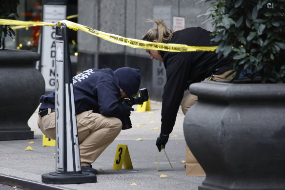 New York police crime scene unit members photograph bullets on the footpath in the hours after the shooting.