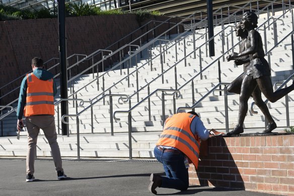 Workers remove the coverings of the plaques on Tuesday afternoon.