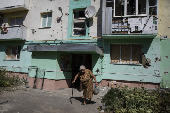 Maria Tiutiunnykova, 81, cleans up glass after a rocket blew out windows in her building in Bakhmut. 