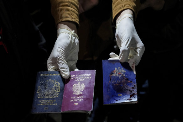 A man displays blood-stained British, Polish, and Australian passports