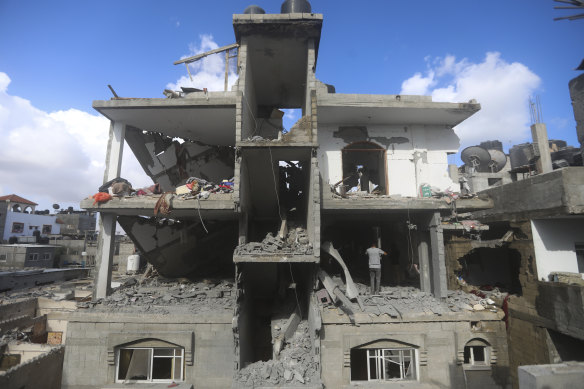 فلسطینی ها به تخریب پس از حمله اسرائیل به یک ساختمان مسکونی در رفح نگاه می کنند.