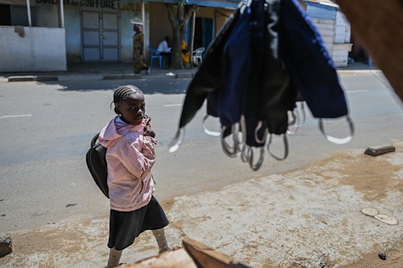 A schoolgirl walks in front of a shop selling facemasks in Bunia.