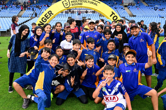 Schoolchildren brave the rain for the launch of the NRL’s Multicultural Round at Belmore yesterday.