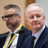 Justin Stevens (background) and Hugh Marks at an estimates hearing in December.